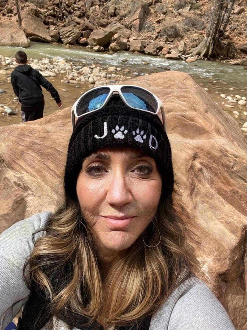 A woman wearing sunglasses and a hat in the mountains.