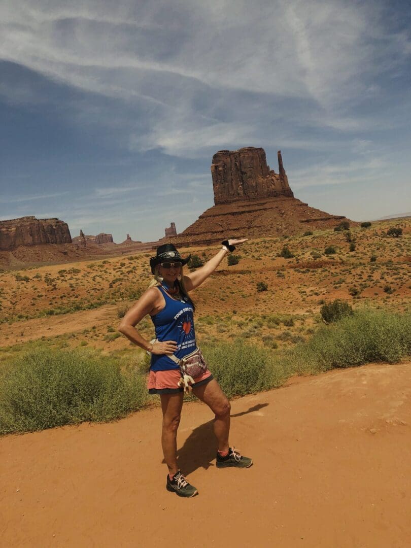 A woman standing on the side of a road in front of some mountains.