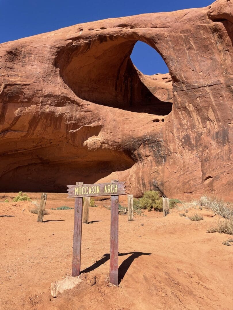 A sign in front of an arch near the desert.