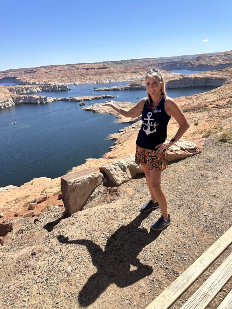 A woman standing on the side of a road near water.