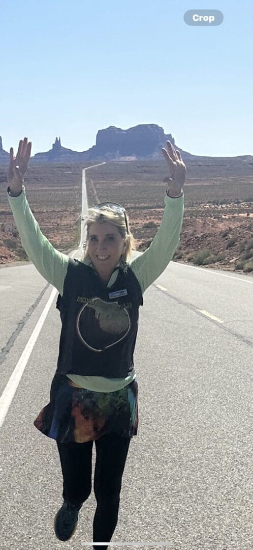 A woman standing on the side of a road with her arms in the air.