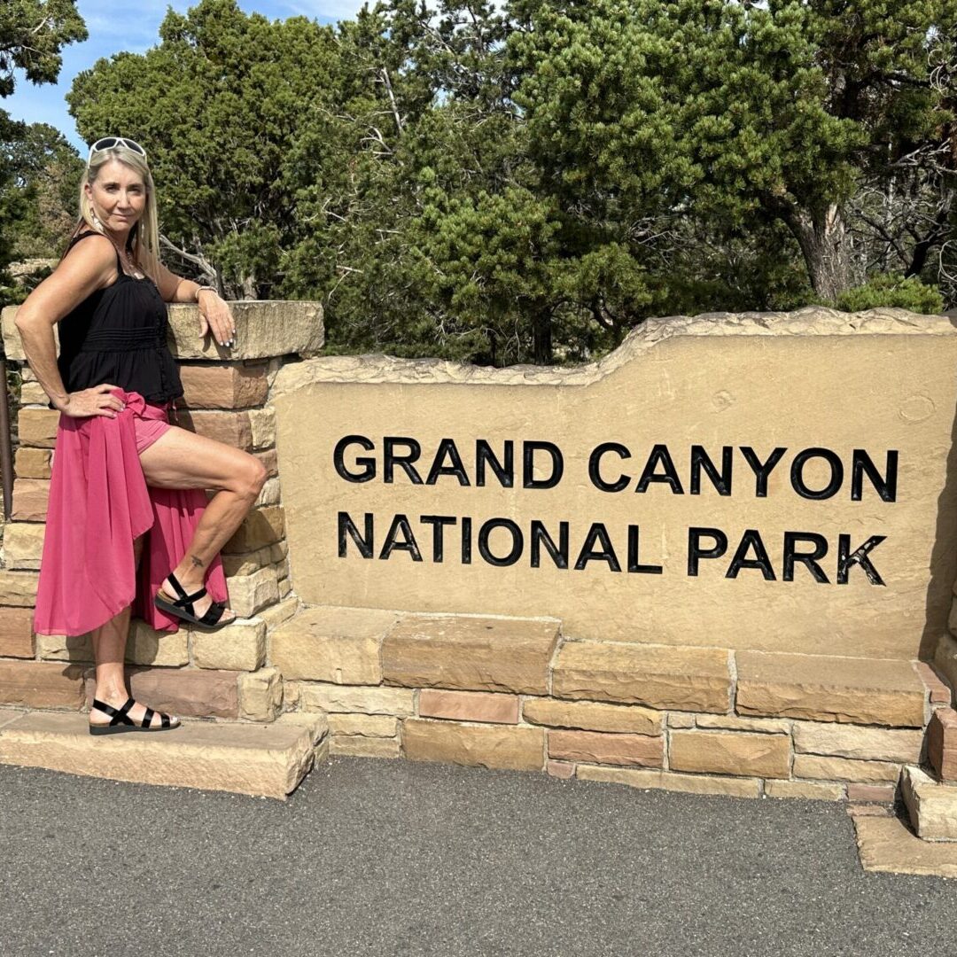 A woman standing in front of the entrance to grand canyon national park.