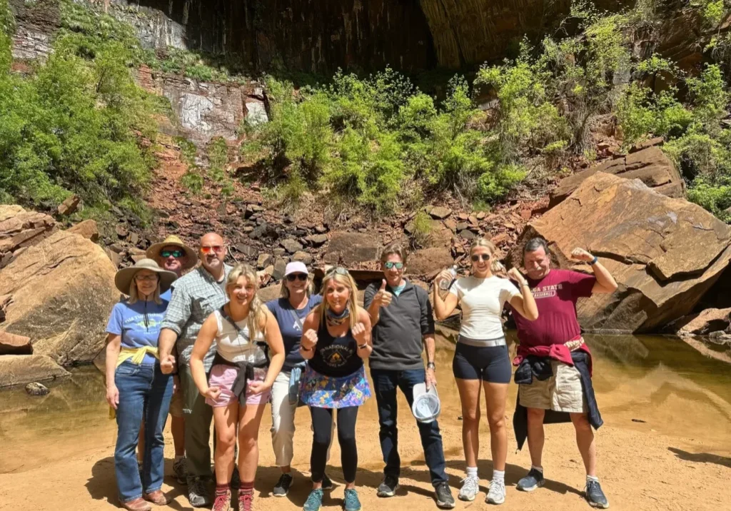 A group of people standing in front of a cave.